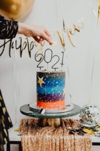 Woman's hand lighting candle that says Happy 2021