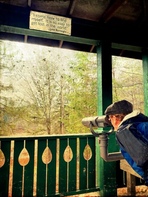 Man looking through scope at scenery, quote in shelter reads "I come here to find myself; it's so easy to get lost in the world. -John Burroughs