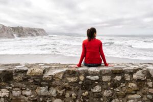 Woman sitting on rocks looking out at the sea