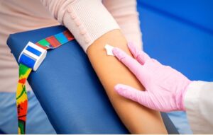 Pink gloved hand placing gauze on patient's arm following blood draw